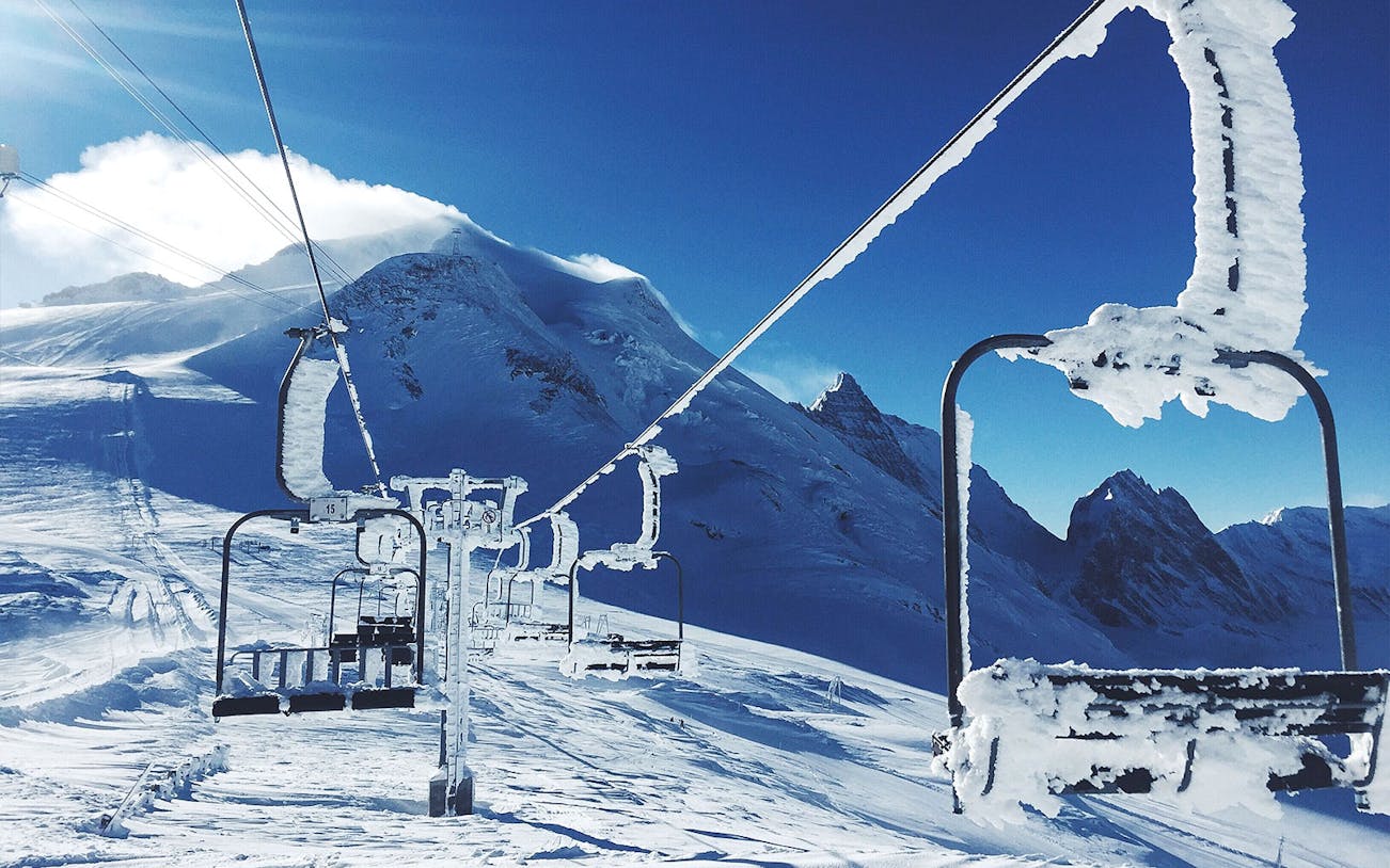 Ski lift covered in snow at Tomamu Ski Resort with mountain backdrop.