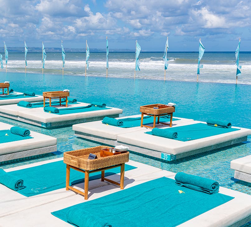 Atlas Beach Club poolside view with sun loungers and palm trees, Bali, Indonesia.