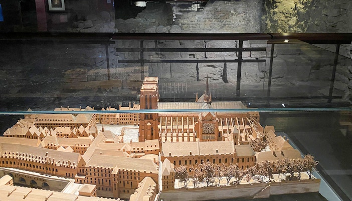 Notre Dame de Paris facade with tourists on outdoor walking tour, entry to cathedral's crypt.