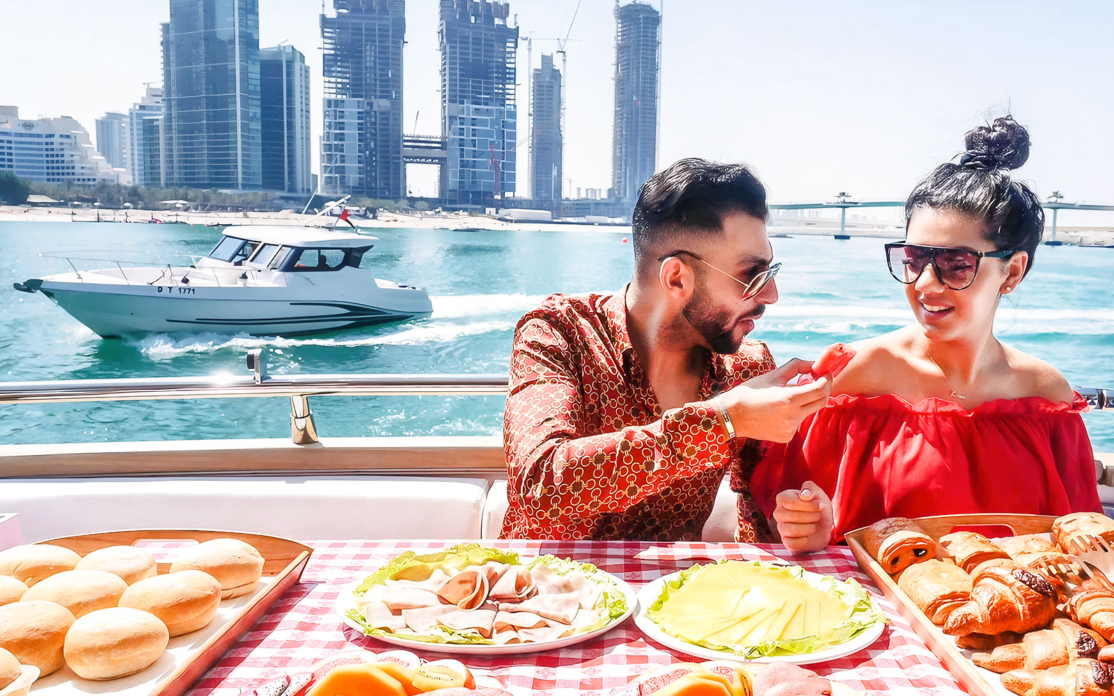 Couple dining on a luxury yacht with Dubai skyline in the background.