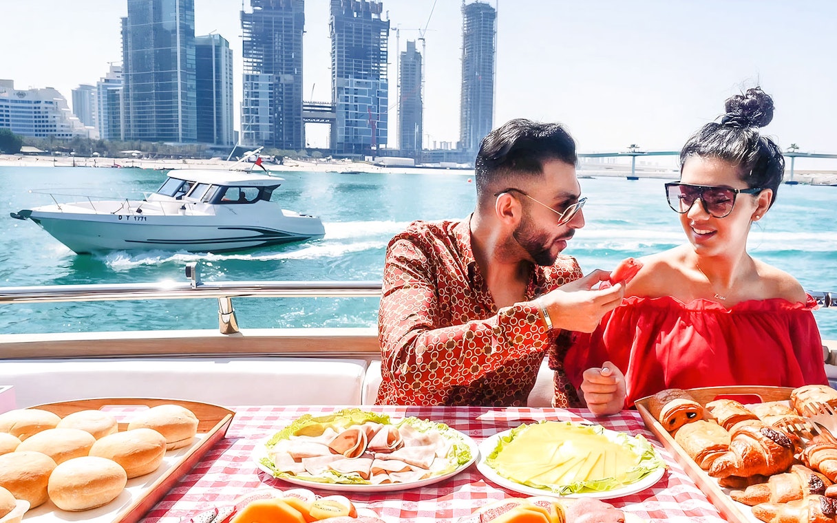 Couple dining on a luxury yacht with Dubai skyline in the background.