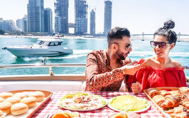 Couple dining on a luxury yacht with Dubai skyline in the background.