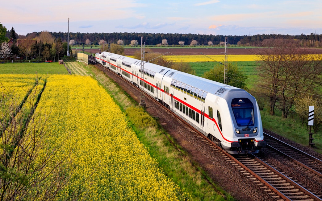 Train traveling through German countryside with yellow fields, related to Interrail Germany Mobile Pass.