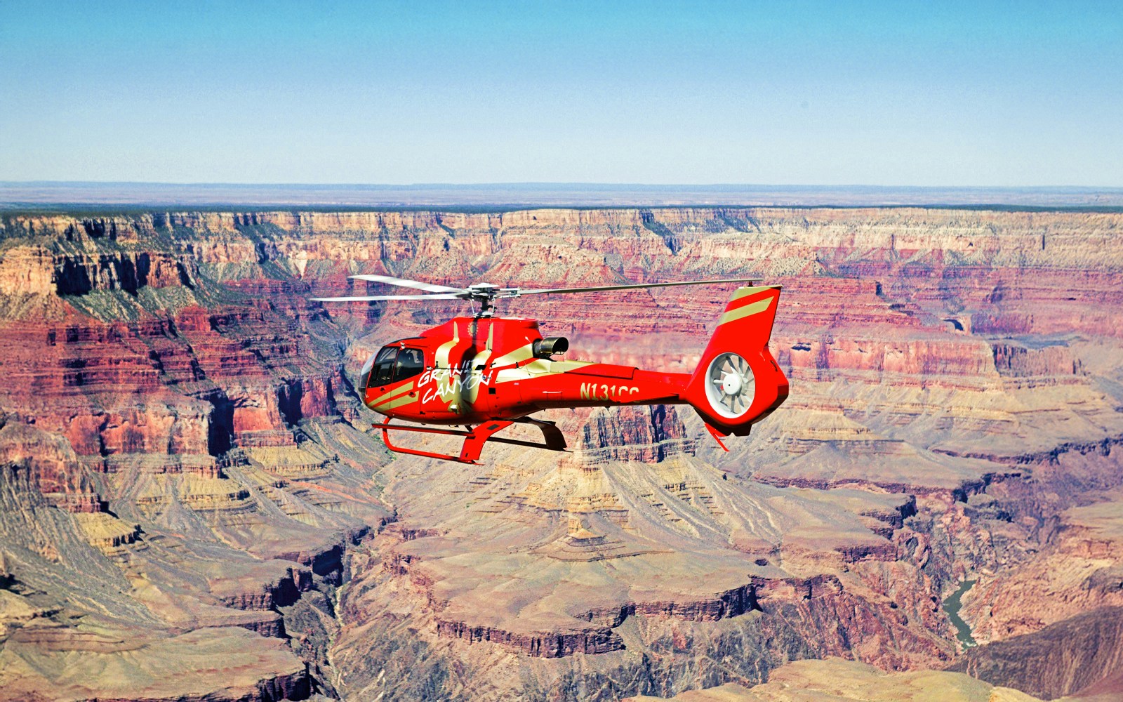 Red helicopter flying over the Grand Canyon.
