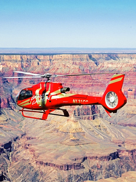 Red helicopter flying over the Grand Canyon.