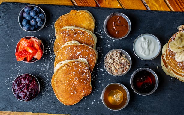 Pancakes with assorted toppings aboard the cruise, including berries, syrup, and nuts.