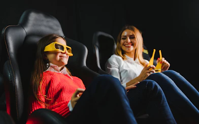 Mother and daughter enjoying 3D movie with glasses in cinema.