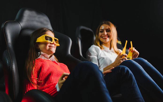 Mother and daughter enjoying 3D movie with glasses in cinema.