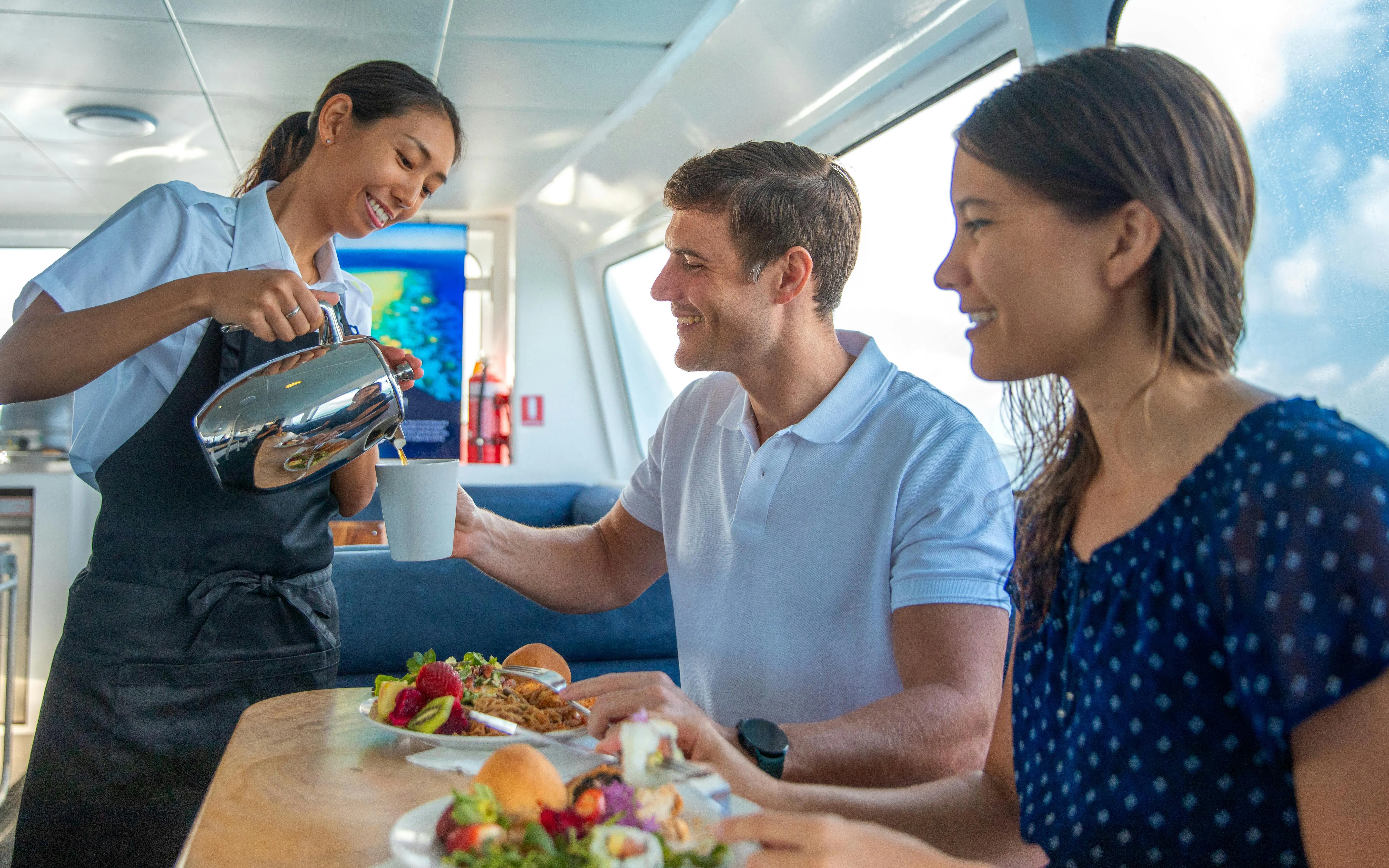 Server pouring coffee for guests on a Cairns snorkelling tour boat.