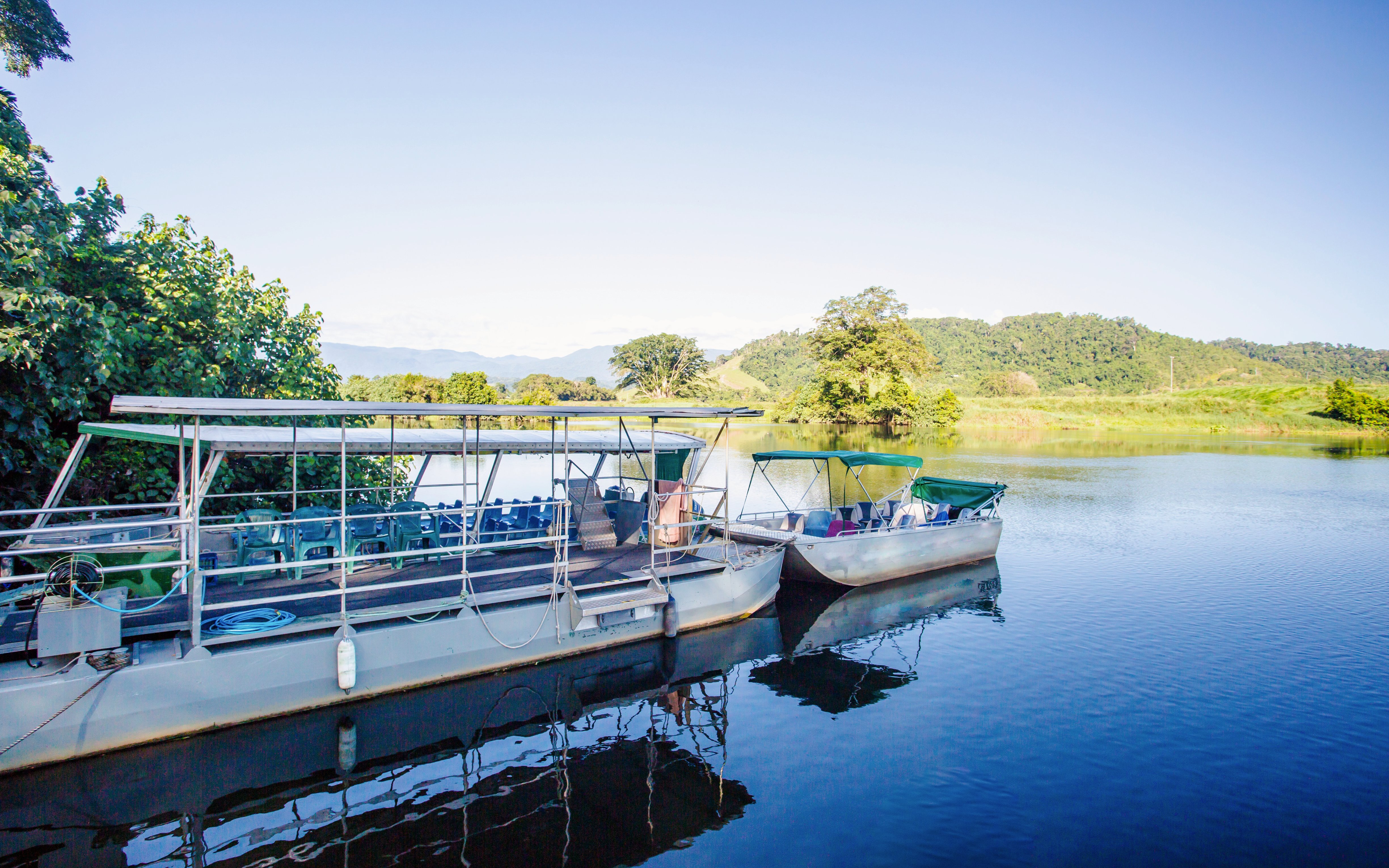 Riverboats docked on the Daintree River with lush greenery in the background.