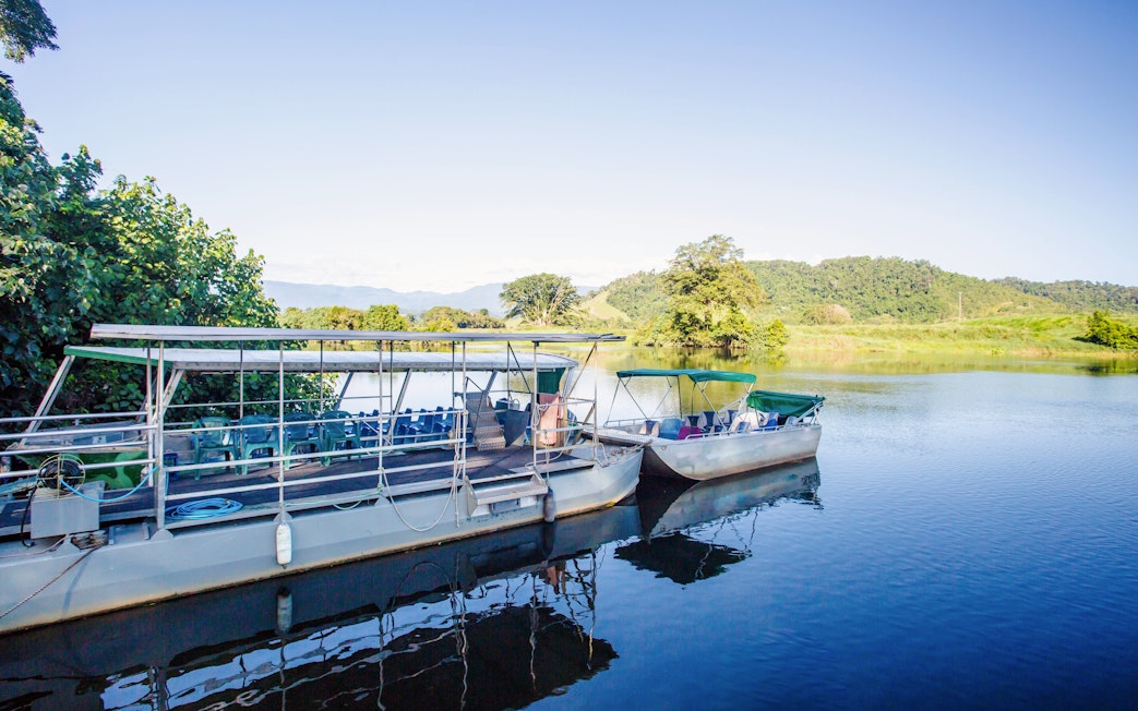 Riverboats docked on the Daintree River with lush greenery in the background.