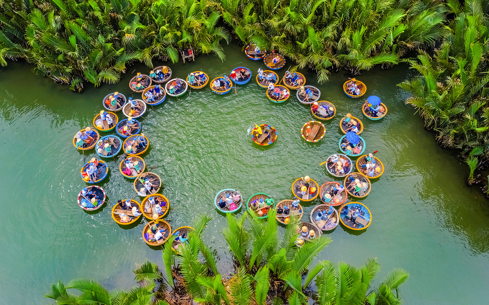 Aerial view of tourists in round bamboo boats on a river surrounded by lush greenery.