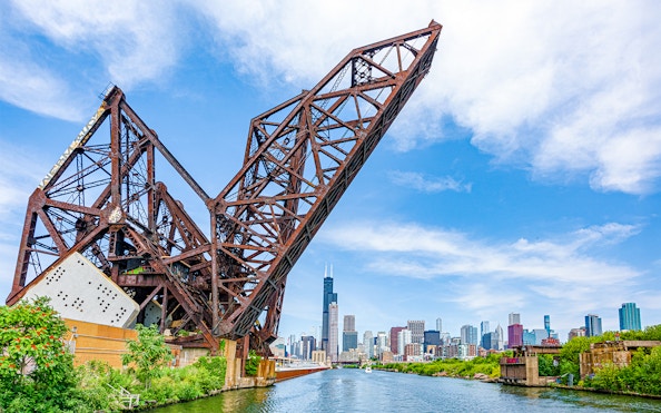 Chicago skyline with Willis Tower viewed from the river, featuring a raised railway bridge.