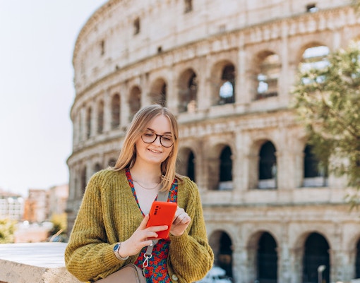 Woman using phone in front of the Colosseum, Rome.