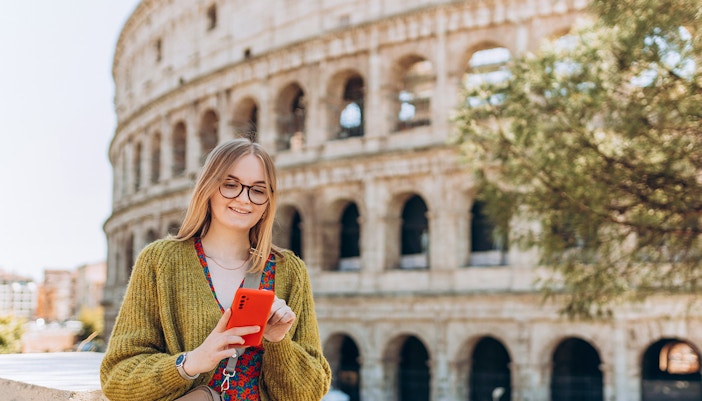 Woman using phone in front of the Colosseum, Rome.