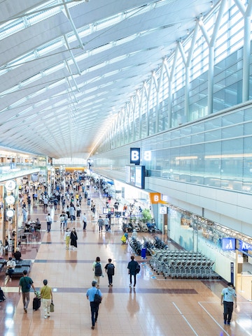 Haneda Airport terminal with travelers walking through concourse, Tokyo, Japan.