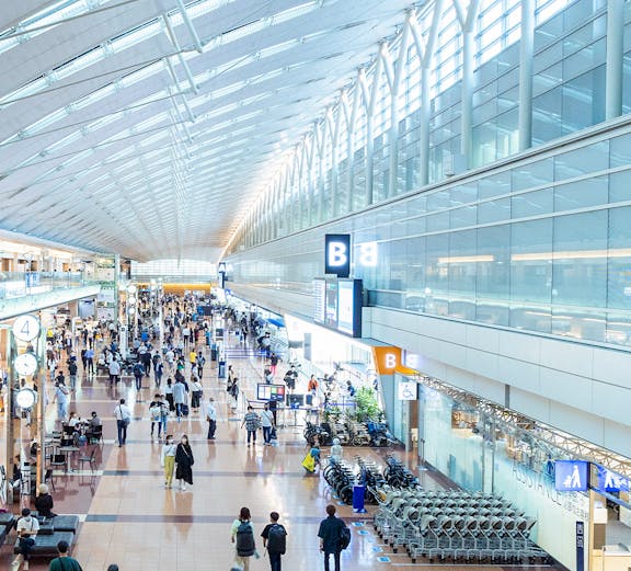 Haneda Airport terminal with travelers walking through concourse, Tokyo, Japan.