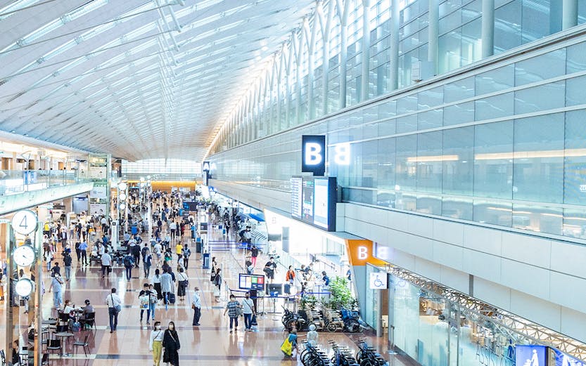 Haneda Airport terminal with travelers walking through concourse, Tokyo, Japan.