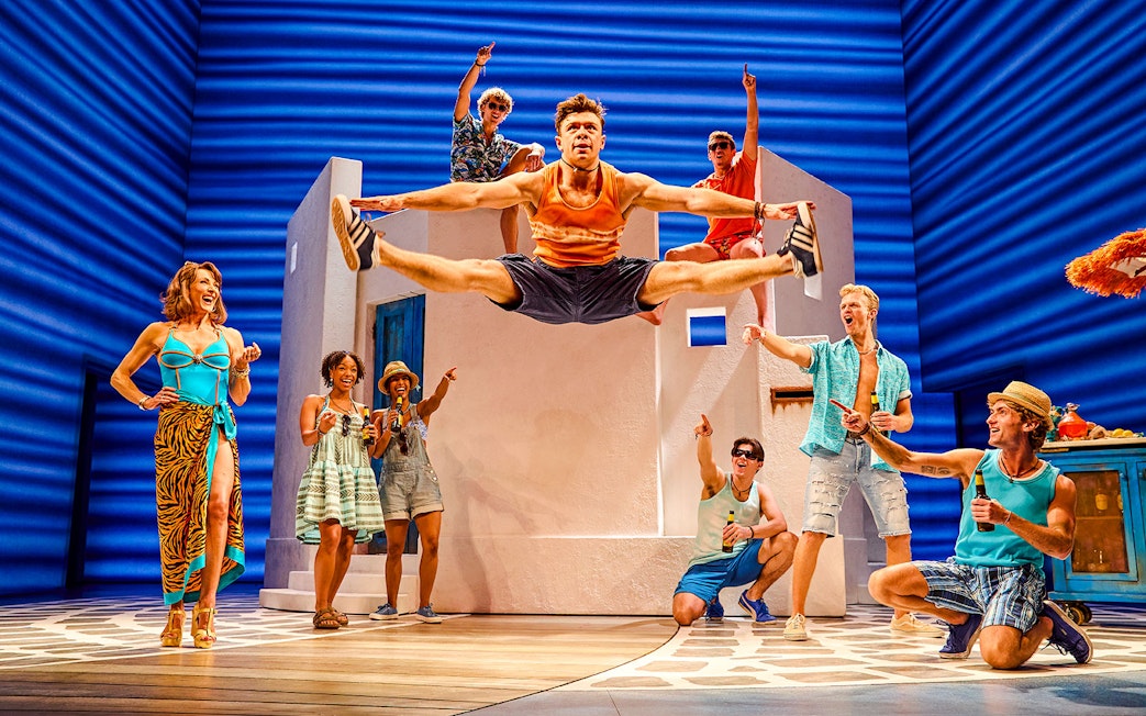 Cast performing energetic dance scene in Mamma Mia production.
