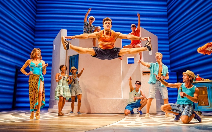 Cast performing energetic dance scene in Mamma Mia production.