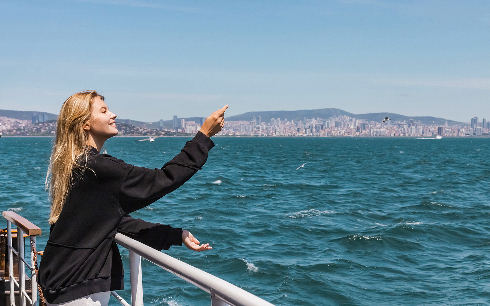 Woman on ferry crossing Bosphorus Strait, Istanbul, gazing at sea.