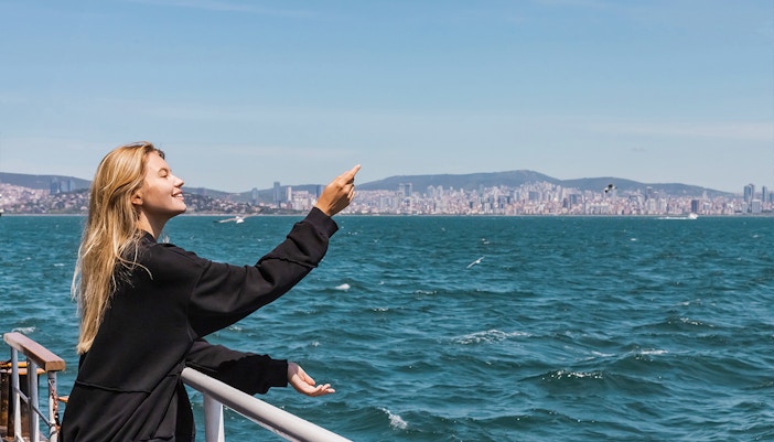 Woman on ferry crossing Bosphorus Strait, Istanbul, gazing at sea.