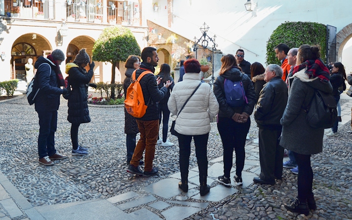 Visitors on a guided tour in the courtyard of Cordoba Mosque-Cathedral and Jewish Quarter.