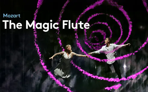 Performers on stage during "The Magic Flute" with swirling pink lights.