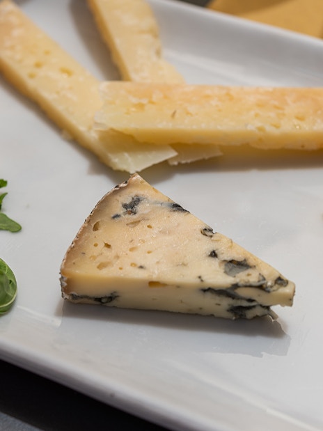 Assorted cheeses with arugula on a plate during a guided food and wine tour in Rome.