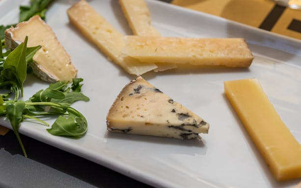 Assorted cheeses with arugula on a plate during a guided food and wine tour in Rome.
