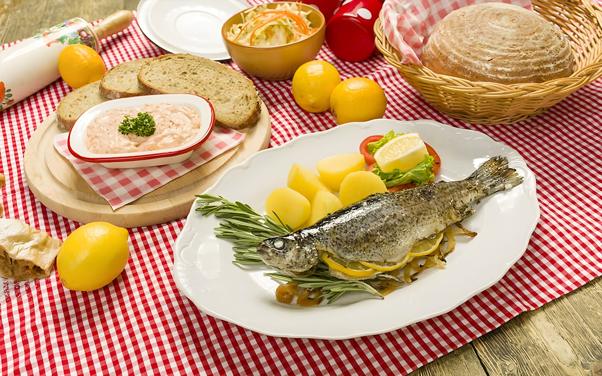 Trot dishes with whole fish, potatoes, and bread at Folklore Dinner Show.