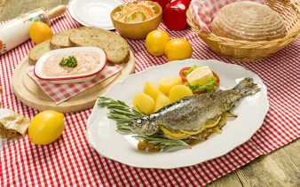 Trot dishes with whole fish, potatoes, and bread at Folklore Dinner Show.