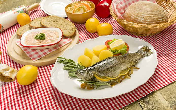 Trot dishes with whole fish, potatoes, and bread at Folklore Dinner Show.