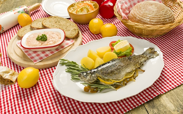 Trot dishes with whole fish, potatoes, and bread at Folklore Dinner Show.