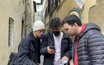 Group exploring Florence alley with a phone for a haunted city game.