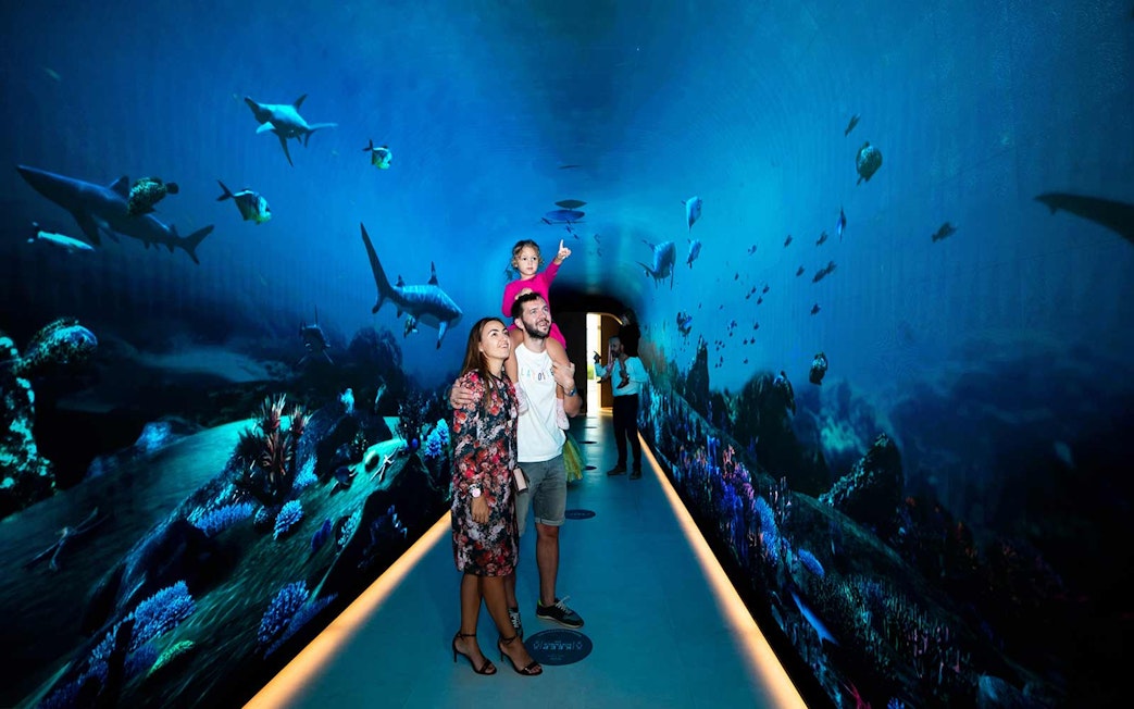 Family exploring underwater-themed tunnel at The View at the Palm, Dubai.