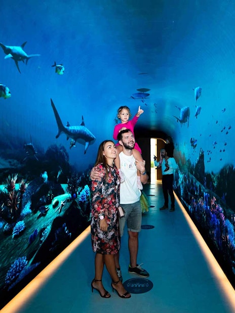 Family exploring underwater-themed tunnel at The View at the Palm, Dubai.