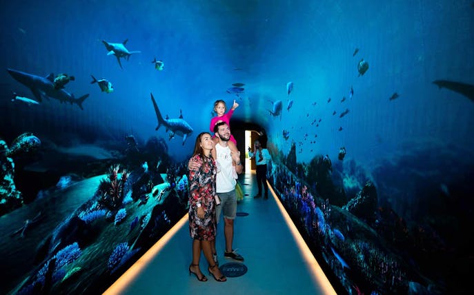 Family exploring underwater-themed tunnel at The View at the Palm, Dubai.