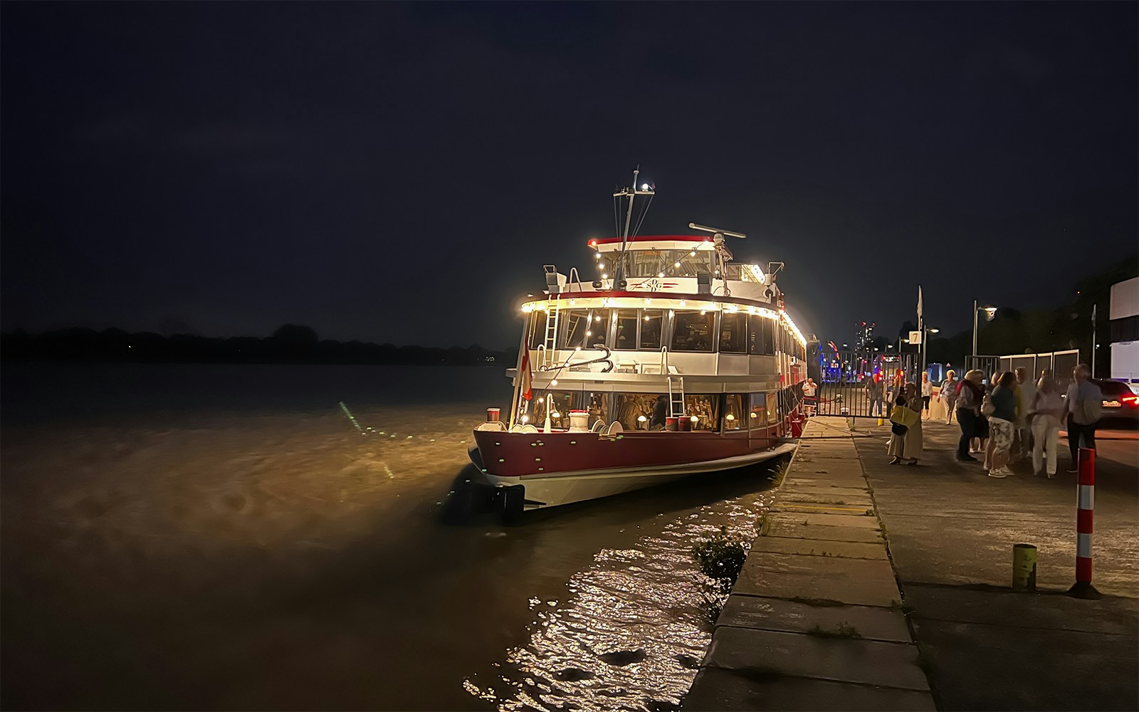 Budapest Danube River dinner cruise boat docked at night with city lights in the background.