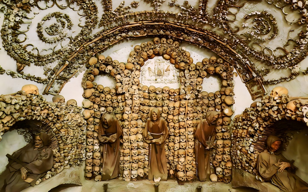 Crypt of the Capuchin Friars in Rome, featuring walls adorned with human skulls and bones.