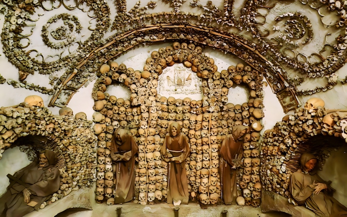 Crypt of the Capuchin Friars in Rome, featuring walls adorned with human skulls and bones.