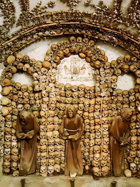 Crypt of the Capuchin Friars in Rome, featuring walls adorned with human skulls and bones.