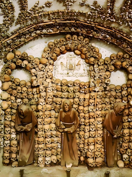 Crypt of the Capuchin Friars in Rome, featuring walls adorned with human skulls and bones.