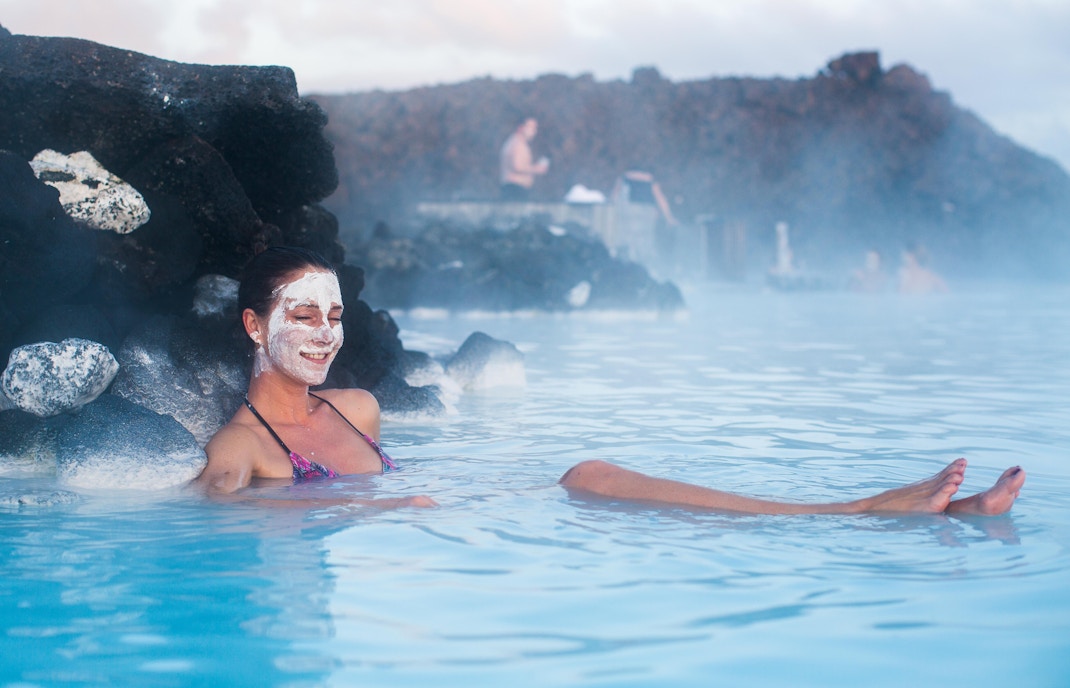 Visitors enjoying the mask bar at Blue Lagoon, Iceland, applying silica mud masks in geothermal spa.