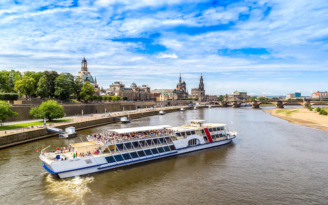 Sightseeing cruise on the Elbe River in Dresden with view of historic buildings and bridge.