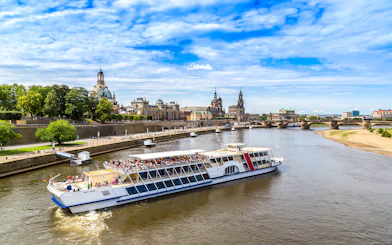 Sightseeing cruise on the Elbe River in Dresden with view of historic buildings and bridge.