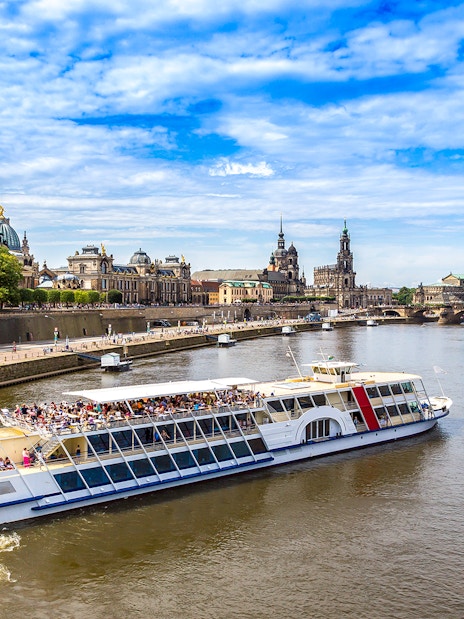 Sightseeing cruise on the Elbe River in Dresden with view of historic buildings and bridge.