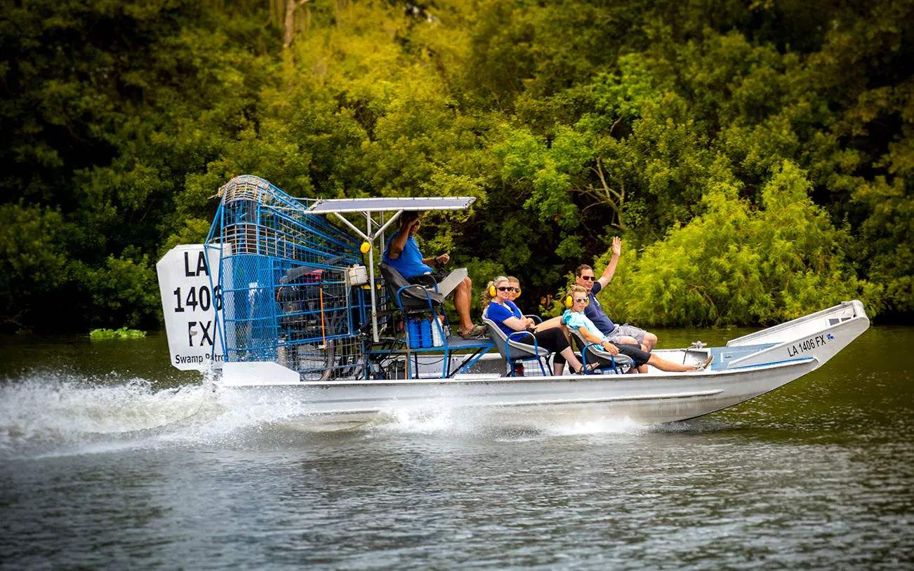 Small airboat with tourists exploring a swamp near New Orleans.