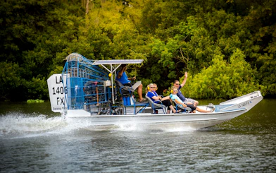 Small airboat with tourists exploring a swamp near New Orleans.
