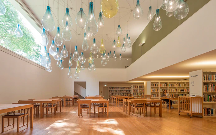 Library interior at Serralves with unique hanging light fixtures and wooden tables.